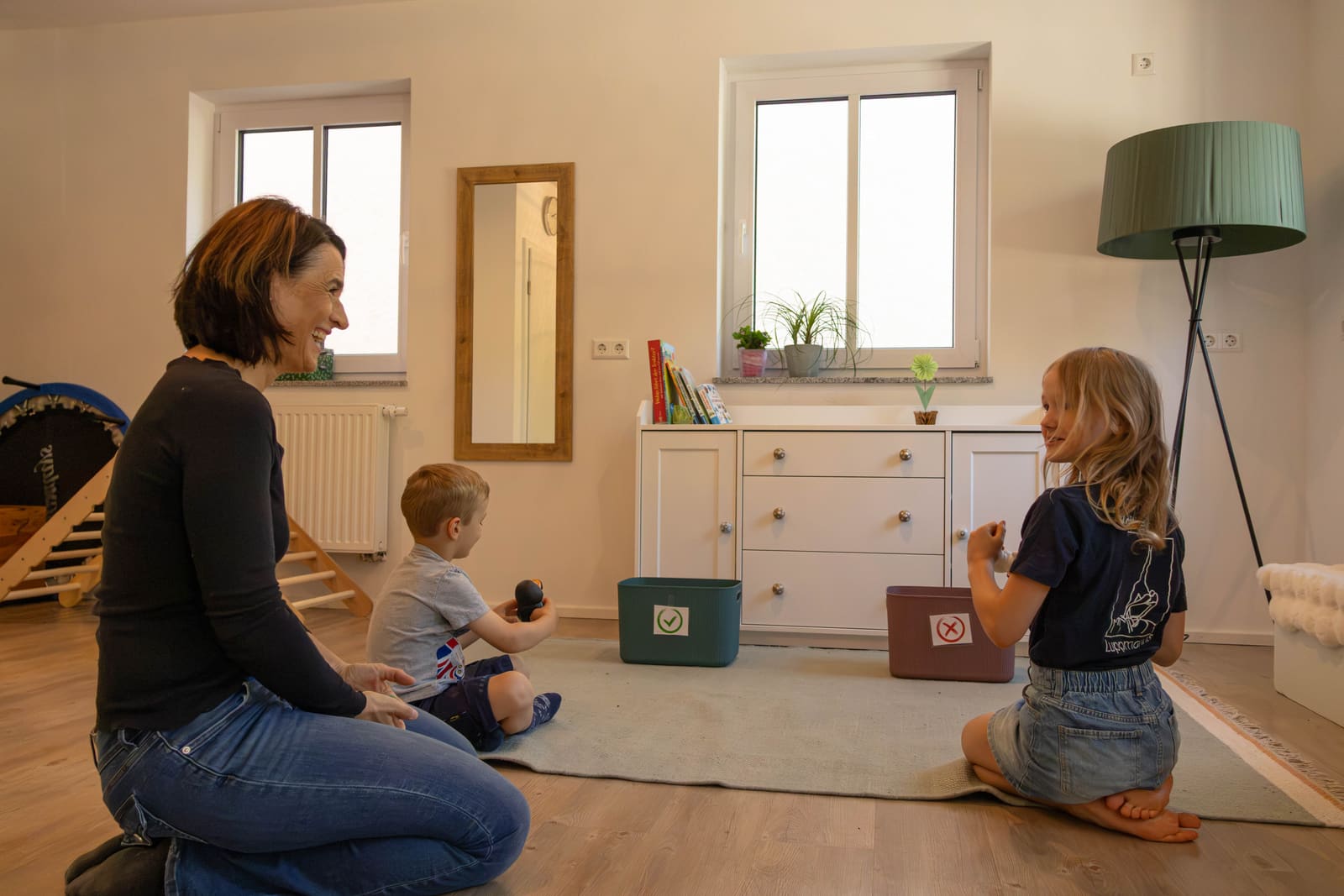 Bewegtes Sortierspiel auf dem Teppich: Kinder ordnen Gegenstände zwei Kisten zu