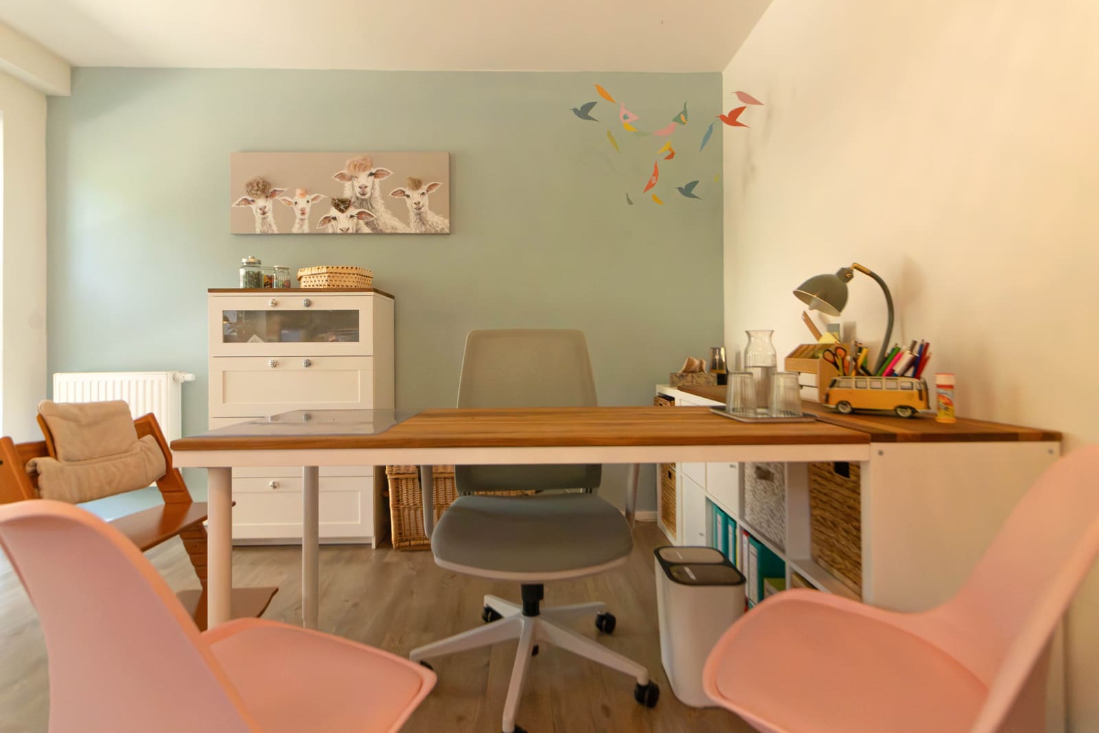 Therapietisch vor mintgrüner Wand mit Kinderstühlen und Materialregal